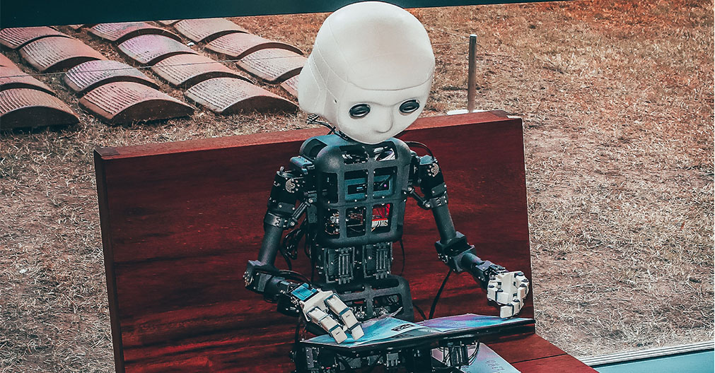 Image: A robot focused on studying digital design, symbolizing the role of AI in revolutionizing the creative process. The robot's intent gaze reflects the potential of automation and innovation in shaping the future of marketing
